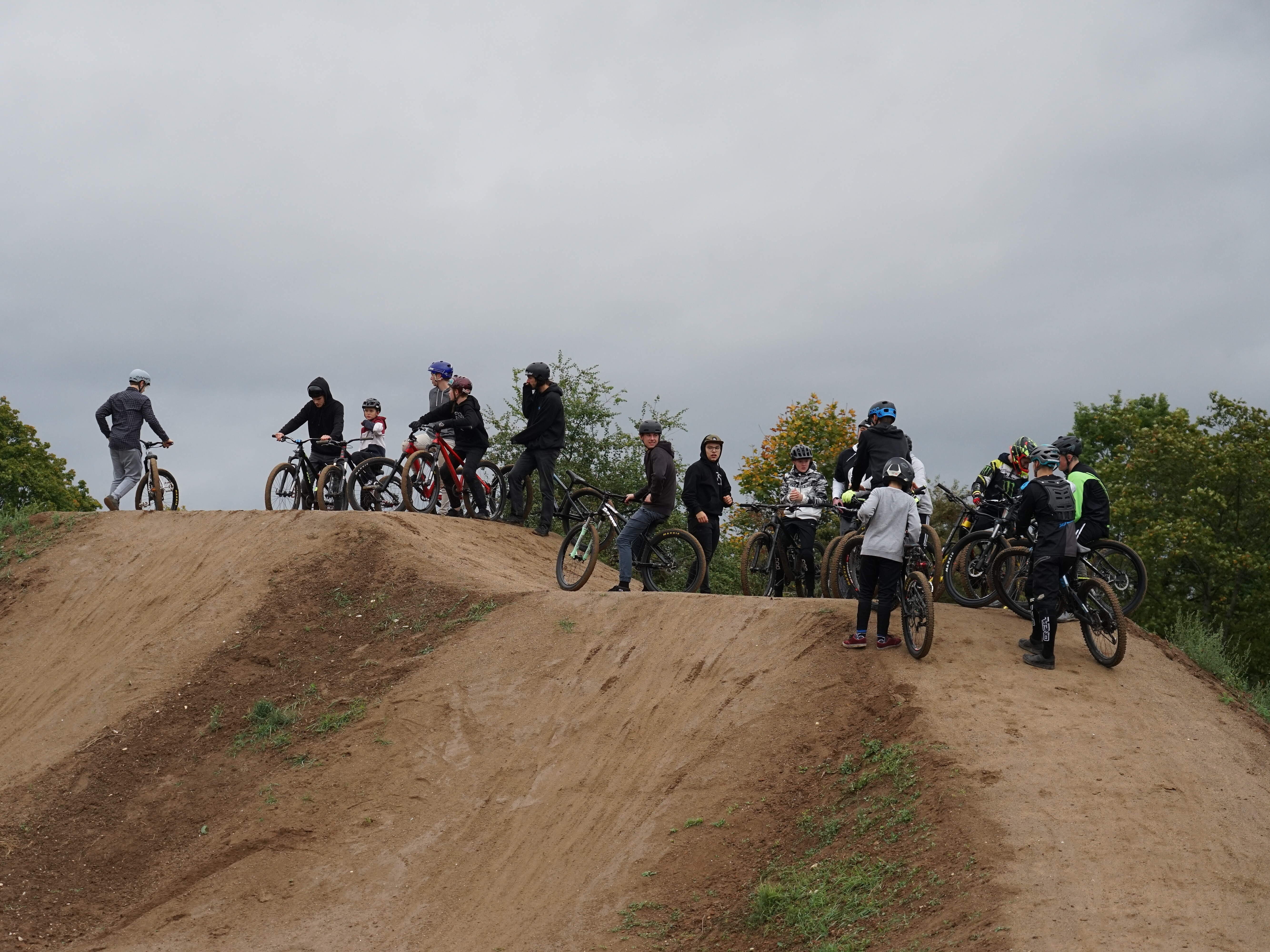 Jugendliche Mountainbiker auf einem Hügel auf einer Mountainbike-Strecke an einem trüben Tag.