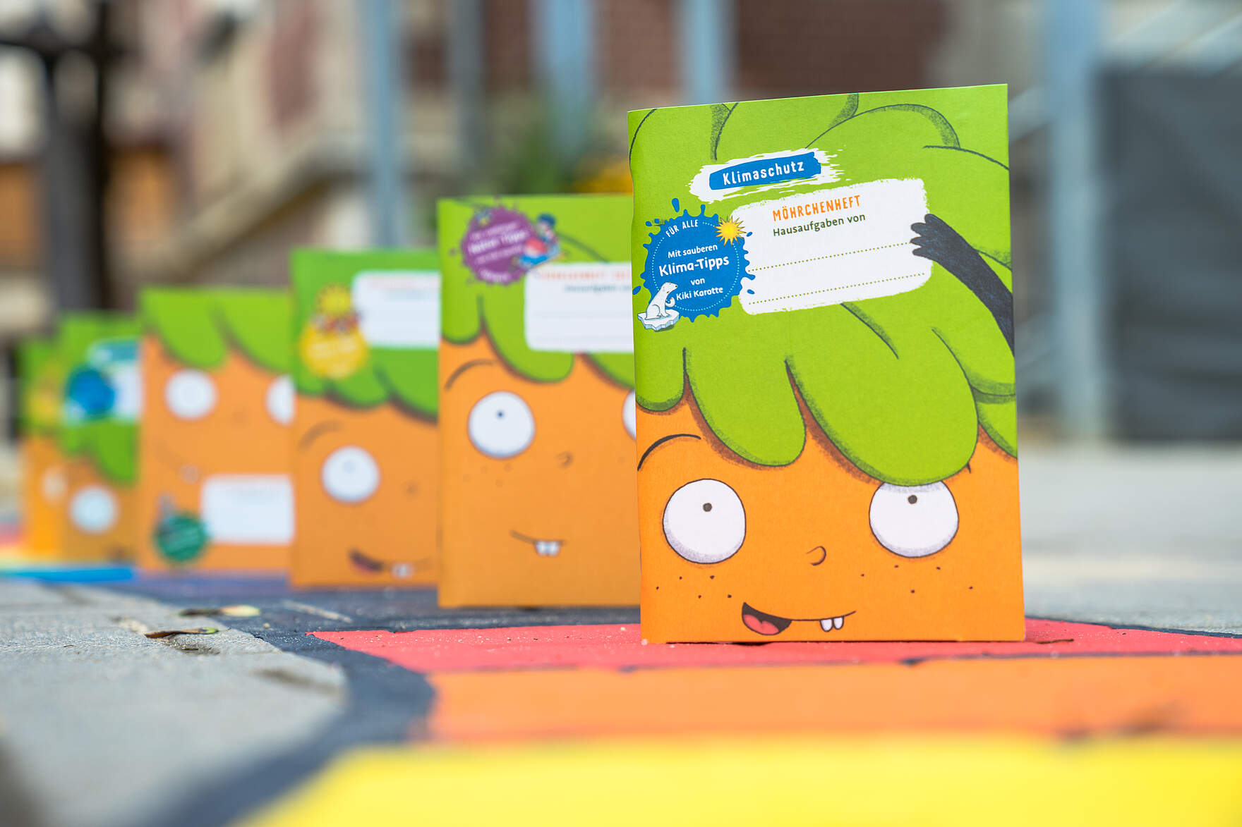 Nachhaltig produziertes Möhrchen-Hausaufgabenheft für den Schulbeginn Das besondere Hausaufgabenheft für Schulanfänger zeigt auf dem Cover eine Illustration einer Karotte mit einem Gesicht.