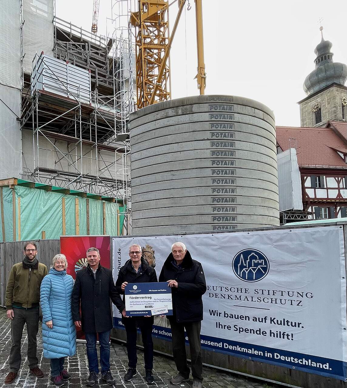 Personen vor der Rathausbaustelle, bei der Übergabe des Schecks