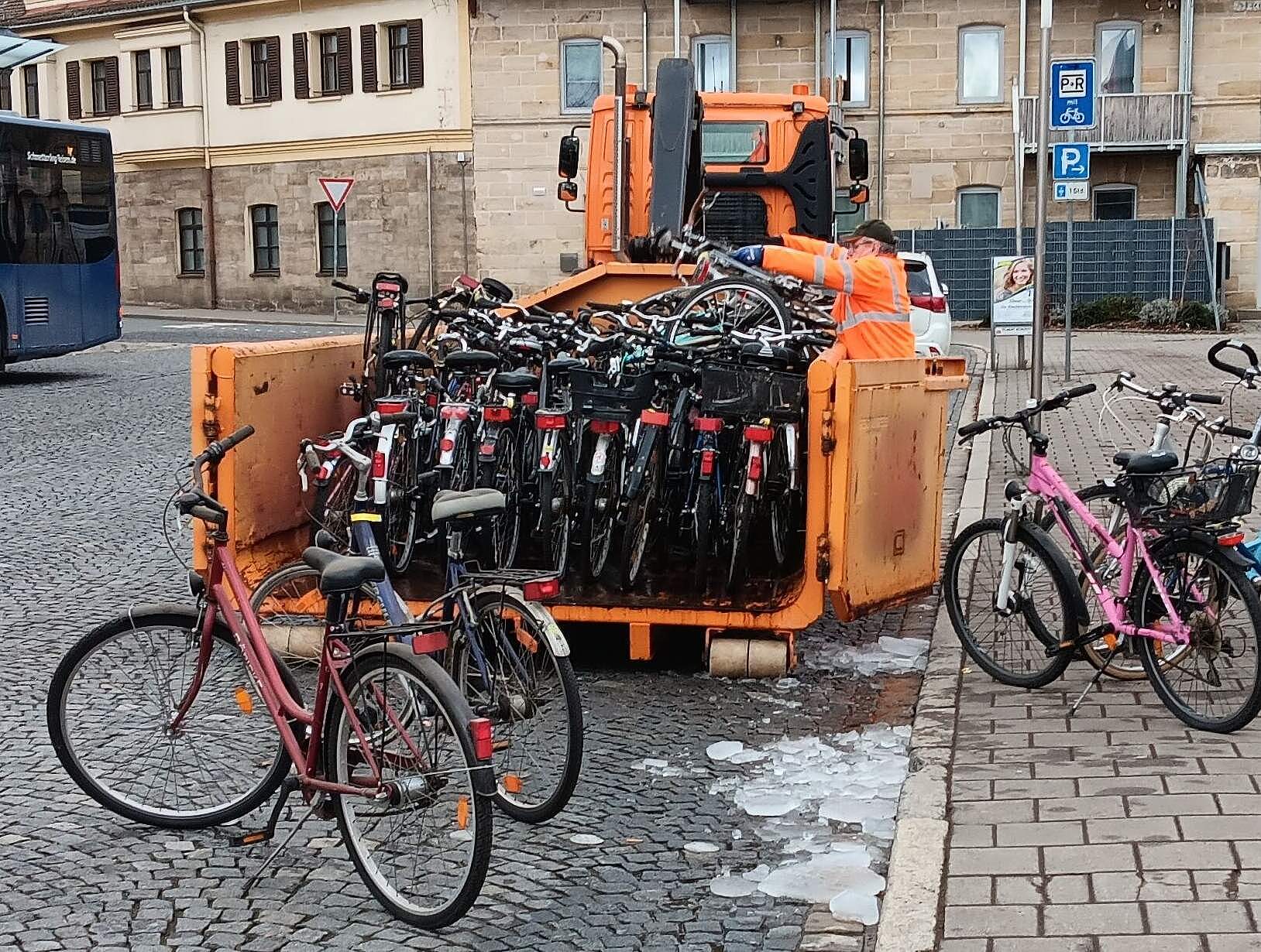 Ein städtischer Arbeiter lädt "herrenlose" Fahhräder, die über einen langen Zeitraum nicht abgeholt wurden am Bahnhof zum Abtransport auf einen Anhänger.