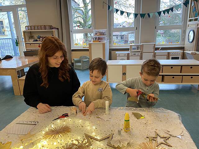 Bastelnde Kinder in der Kindergartengruppe mit einer Erzieherin