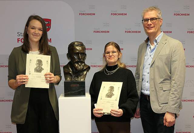 Oberbürgermeister Dr. Uwe Kirschstein (rechts im Bild) überreichte die Urkunden aus der Professor-Georg-Mayer-Franken-Lebert-Stipendienstiftung an Svenja Leonie Palla und an Maja Ketscher. In der Mitte steht die Büste von Georg Mayer Franken.