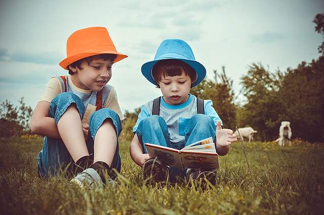 Lesende Kinder auf einer Wiese