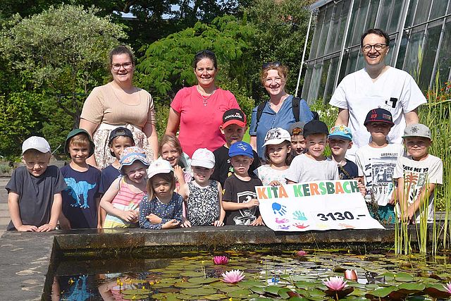 Gruppe mit Erwachsenen und Kindern halten ein Plakat mit einer Spendensumme in der Hand.