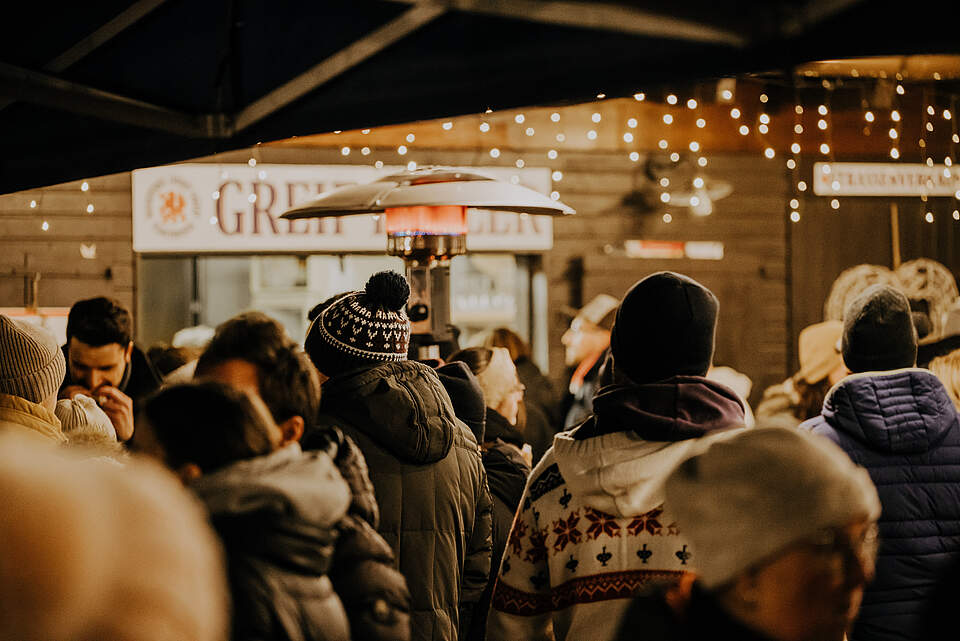 Weihnachtsmarktstand mit Personen im Vordergrund