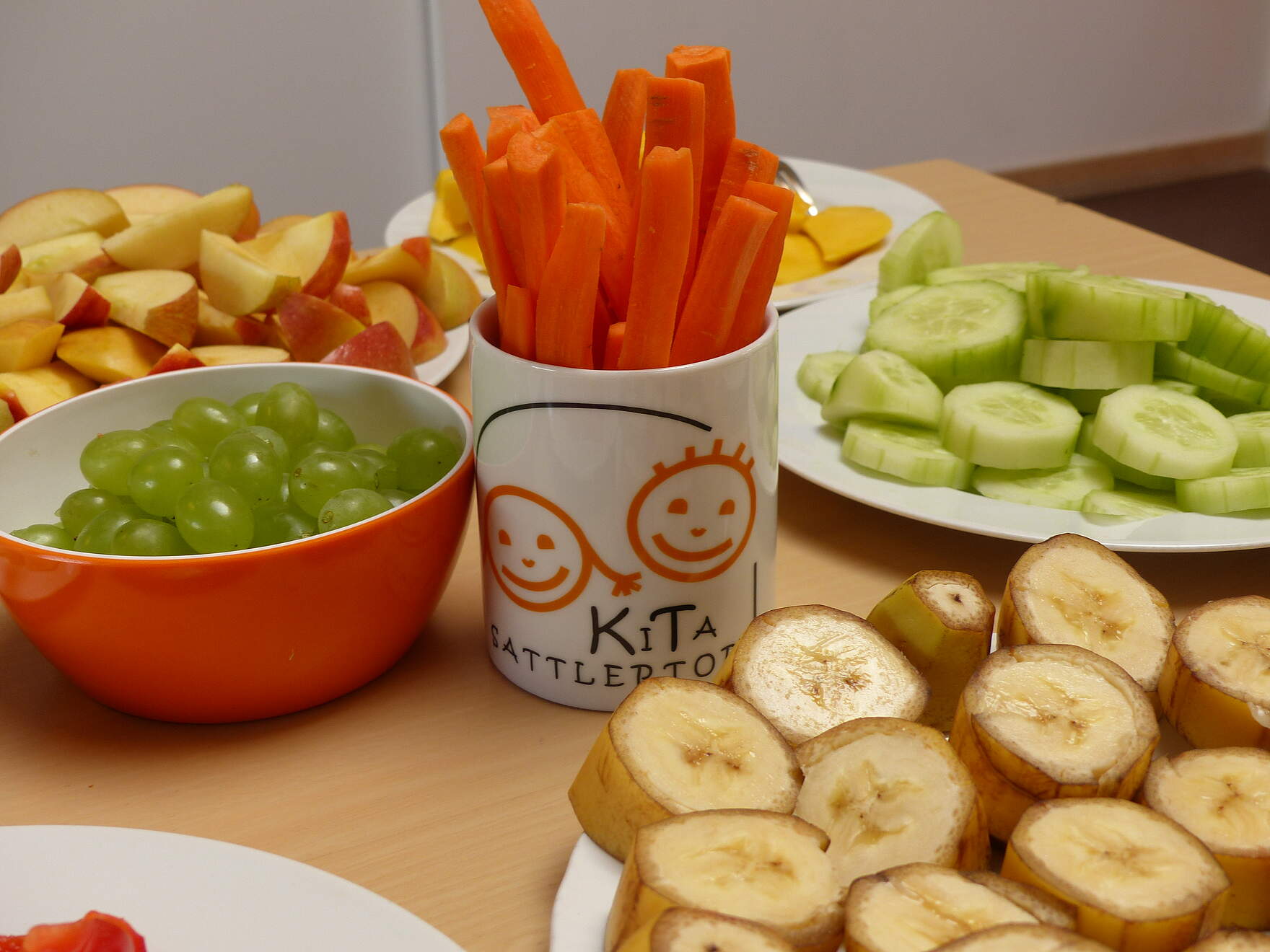 Aufgeschnittenes Obst und Gemüse liegen auf verschiedenen Tellern auf einem Tisch.