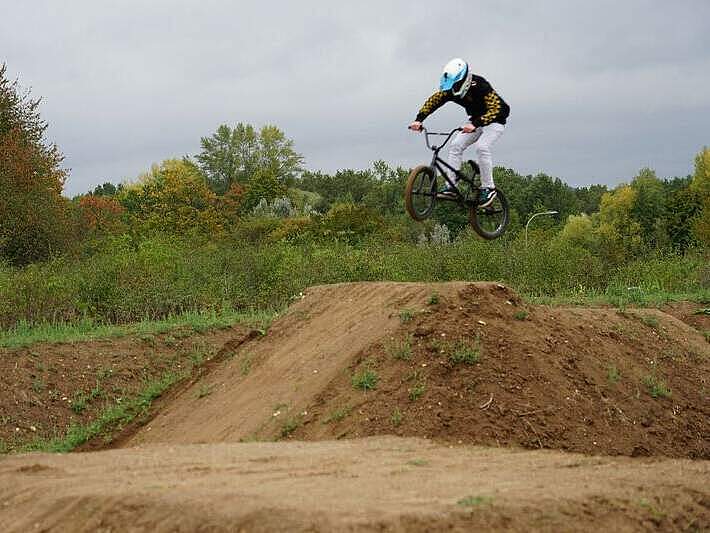 Ein Mountainbiker bei einem Sprung über einen aufgeschütteten Erdhügel.