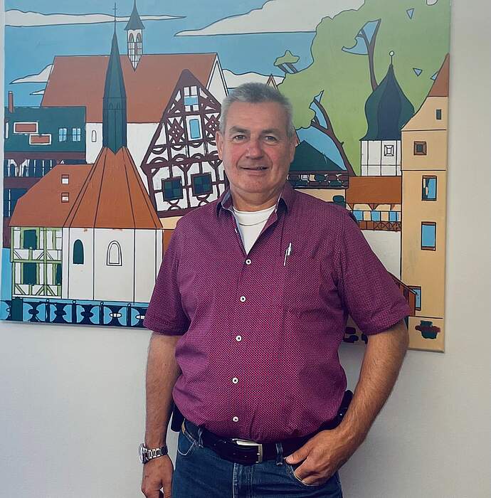 Bauhofleiter der Stadt Forchheim: Ernst Messingschlager Portrait des neuen Bauhofleiters Ernst Messingschlager, der vor einem großformatigen Bild des Forchheimer Katharinenspitals steht.