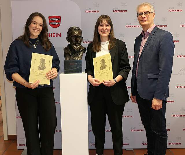 Studentinnen mit Oberbürgermeister neben Büste.