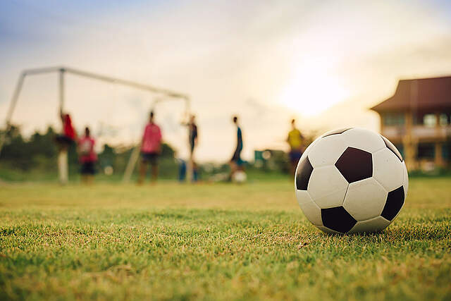 Fußball im Vordergrund dahinter Tor und Kinder beim Spiel