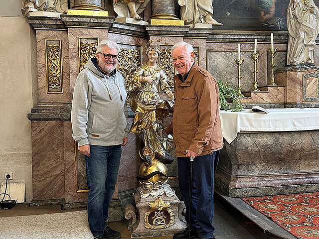 Zwei Personen in einer Kirche mit einer Figur der Maria.