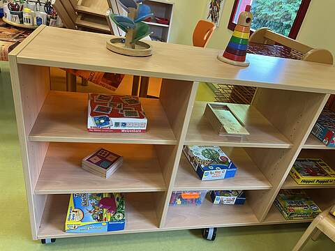 Vielfältige Spieleauswahl im Gruppenraum In einem Regal in einem Kindergartengruppenraum stehen verschiedene Kinderspiele zur Auswahl bereit.