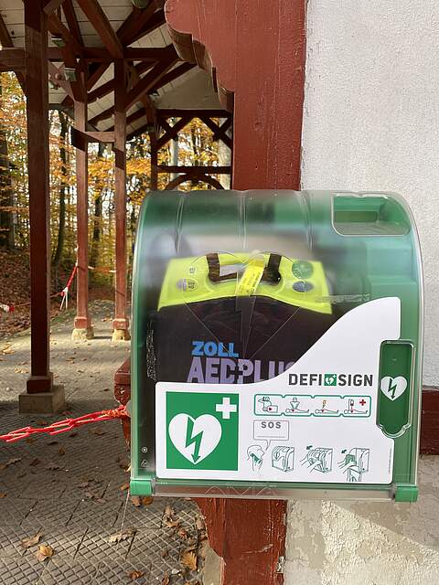 Defibrillator (AED) im Forchheimer Kellerwald am "Glückshafen" Ein Schutzgehäuse mit einem Defibrillator (AED) hängt an einem Gebäude öffentlich zugänglich im Kellerwald.