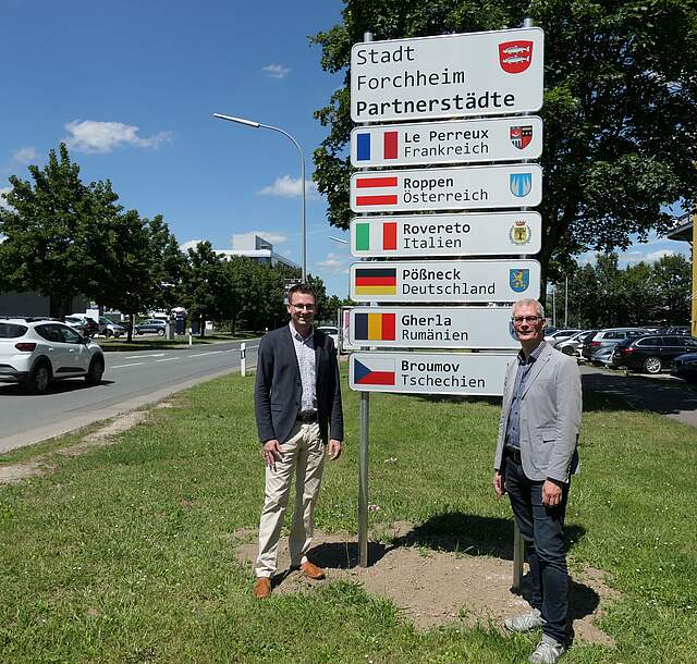 Foto des Oberbürgermeisters Dr. Uwe Kirschstein mit dem Leiter des Amts für Marketing, Tourismus und Int. Beziehungen Nico Cieslar vor dem Partnerschaftsschild in Forchheim-Süd.