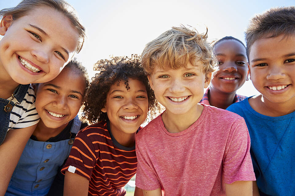 Eine lachende Kindergruppe sieht in die Kamera.