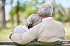 Seniorenpaar auf umarmt sich auf einer Bank.