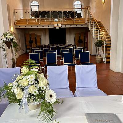 Der Innenraum der Kapelle St. Gereon mit Empore, Stuhlreihen und weißem Blumenschmuck auf dem Tisch des Standesbeamten.