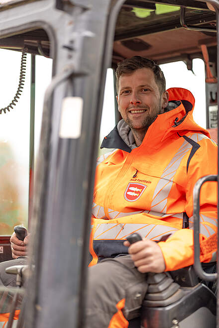 Mitarbeiter im Straßenbau auf einem Bagger