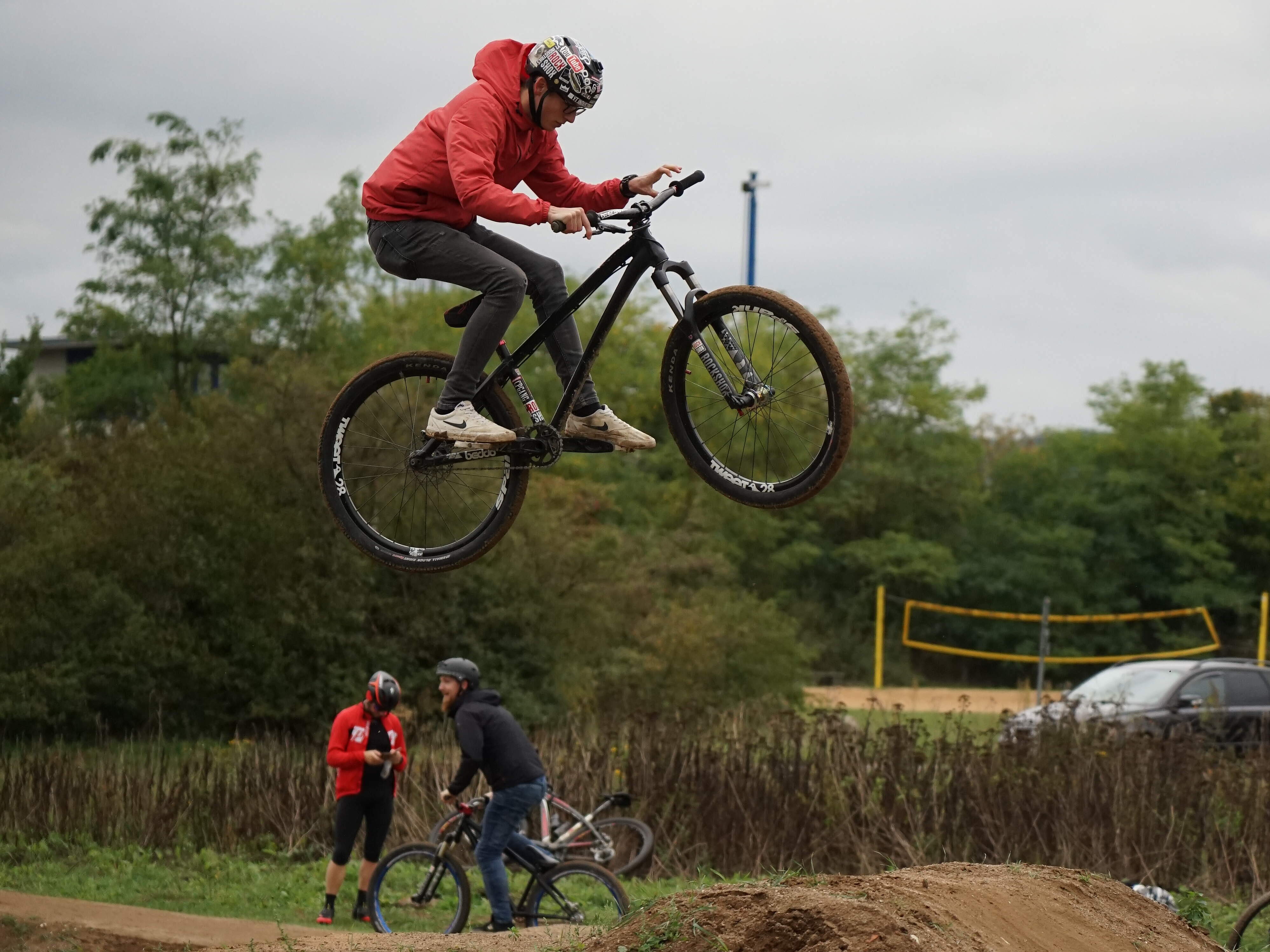 Ein Mountainbiker bei einem Sprung über einen aufgeschütteten Erdhügel.