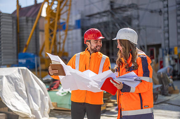 Mitarbeitende des Bauamtes auf einer Baustelle mit Bauplänen