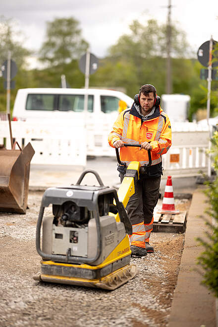 Mitarbeiter im Straßenbau mit Rüttelmaschine