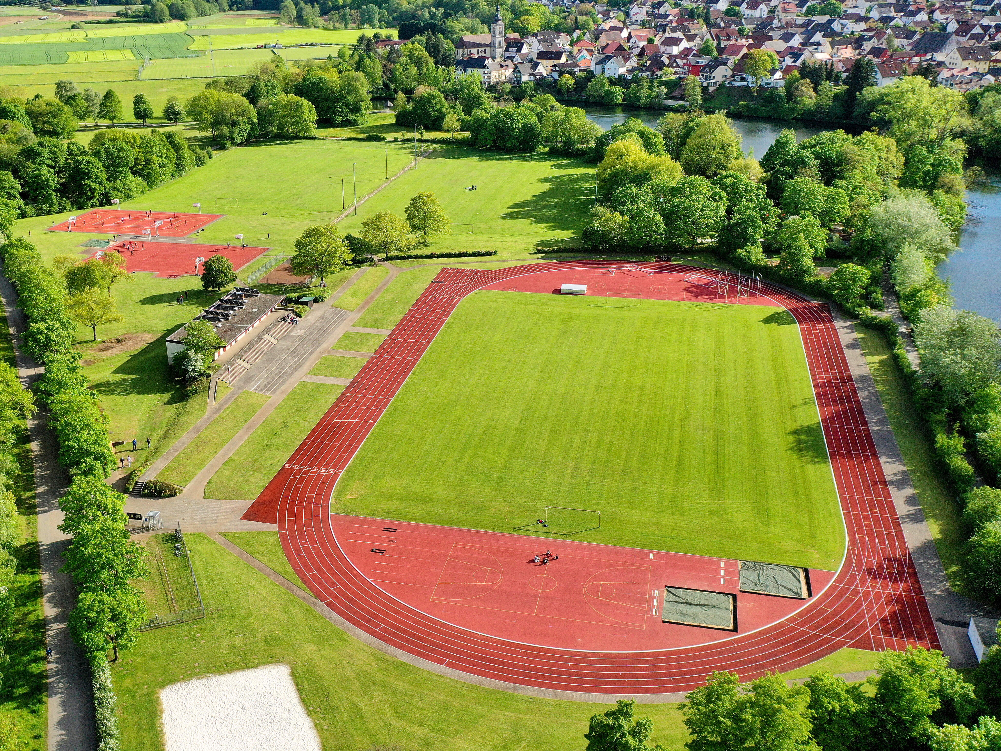 Sportanlagen auf der Sportinsel in Forchheim Luftbildaufnahme der Sportinsel in Forchheim mit Fußballfeld, Lauftbahn und weiteren Outdoorsportanlagen. Die große Grünanlage ist von zwei Seiten umgeben von Flüssen.