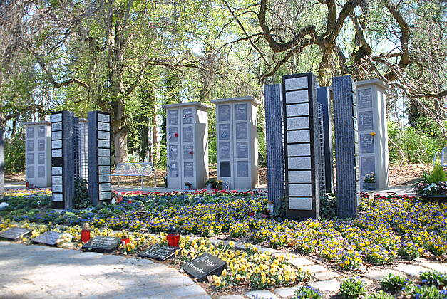 Moderne Urnenstelenanlage mit Blumenbeeten mit Frühjahrsbepflanzung