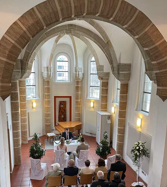 Innenansicht einer Kapelle mit hoher Gewölbedecke, in der eine Trauung stattfindet.