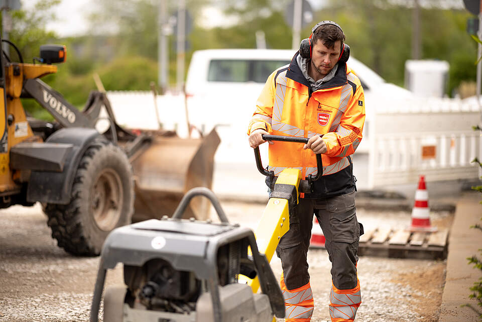 Mitarbeiter im Straßenbau mit Rüttelmaschine