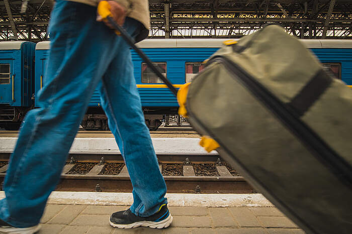 Ukraine Flüchtling am Bahnhof, der einen Koffer hinter sich herzieht.