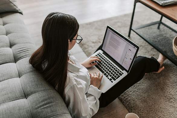 Onlinebewerbung Frau sitzt auf dem Boden mit Laptop auf dem Schoß