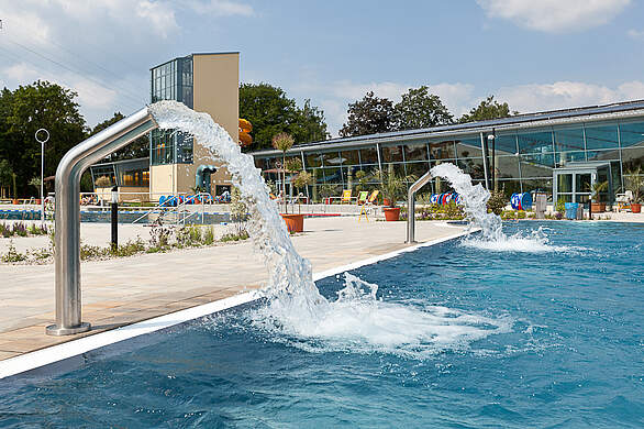 Zwei Außenwasserwasserfallanlagen an einem Außenbecken in einem Freizeitbad.