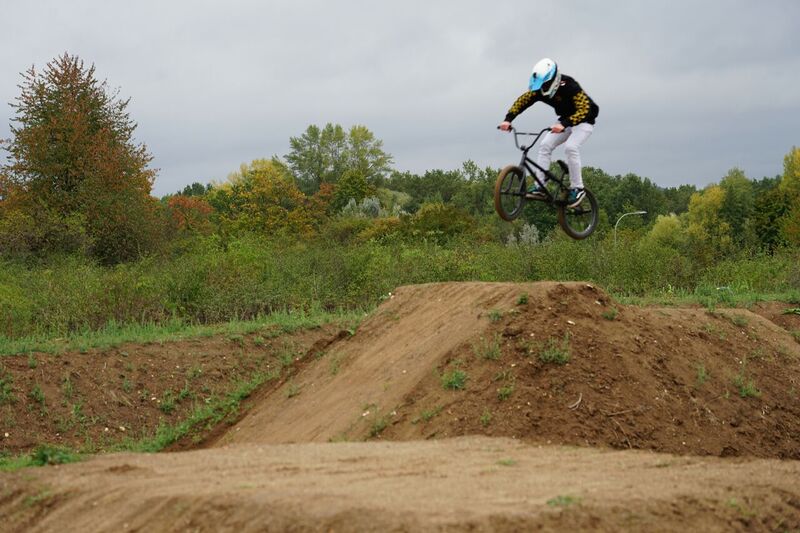 Ein Mountainbiker bei einem Sprung über einen aufgeschütteten Erdhügel.