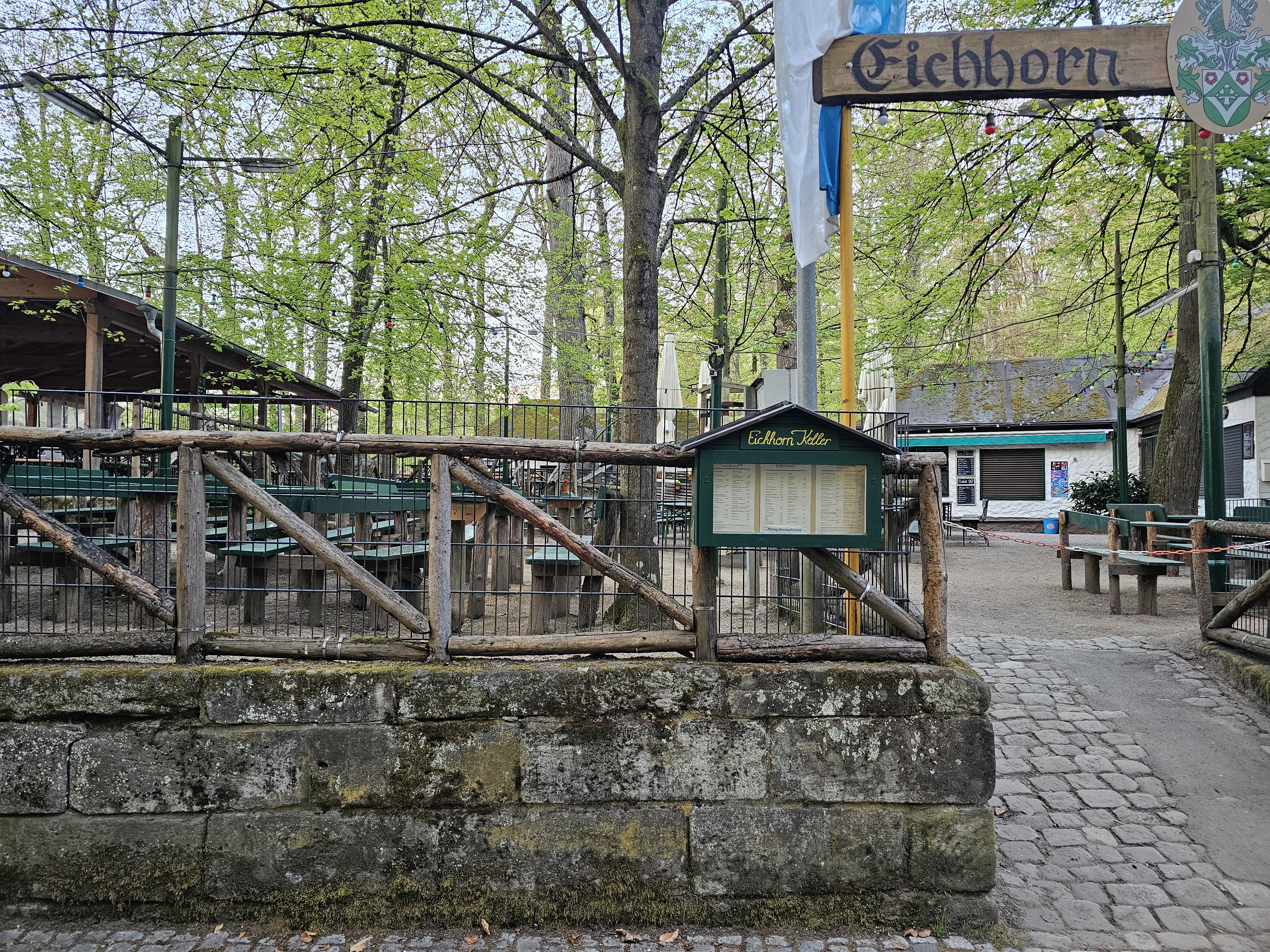 Eichhorn-Keller Eingangsbereich zum Eichhornkeller mit Sandsteinmauer und Biergarten-Garnituren im Forchheimer Kellerwald