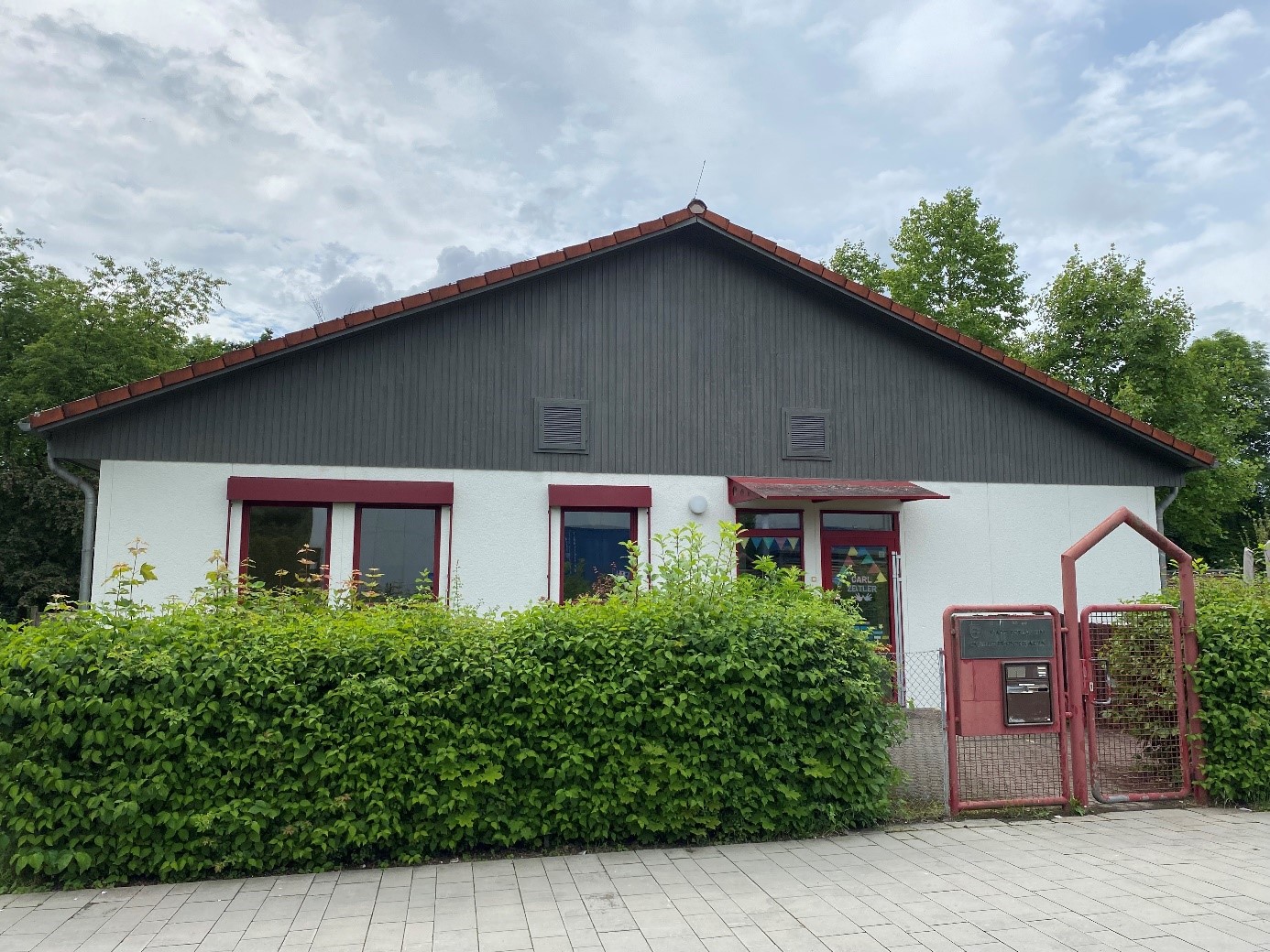 Eingangsbereich des Carl-Zeitler Kindergartens Eingangsbereich des Carl-Zeitler Kindergartens. Davor eine grüne Hecke und ein rotes Eingangstor