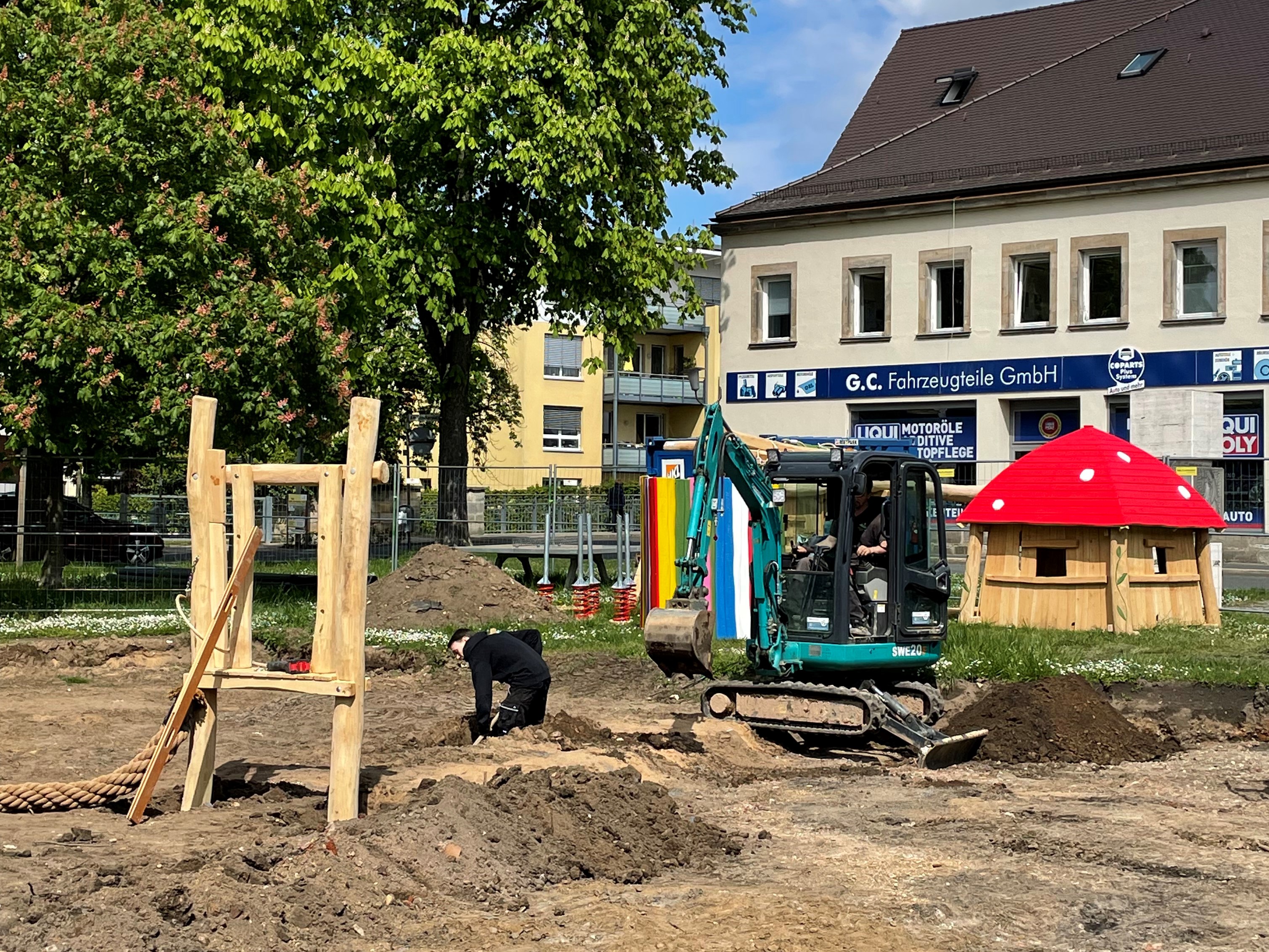 Aufbau der Kletter- und Balanciergeräten sowie einem Spielhaus am Mehrgenerationespielplatz. Ein Holzspielhaus mit buntem Dach, Kletter- und Balanciergeräte werden auf einem Spielplatz aufgebaut.
