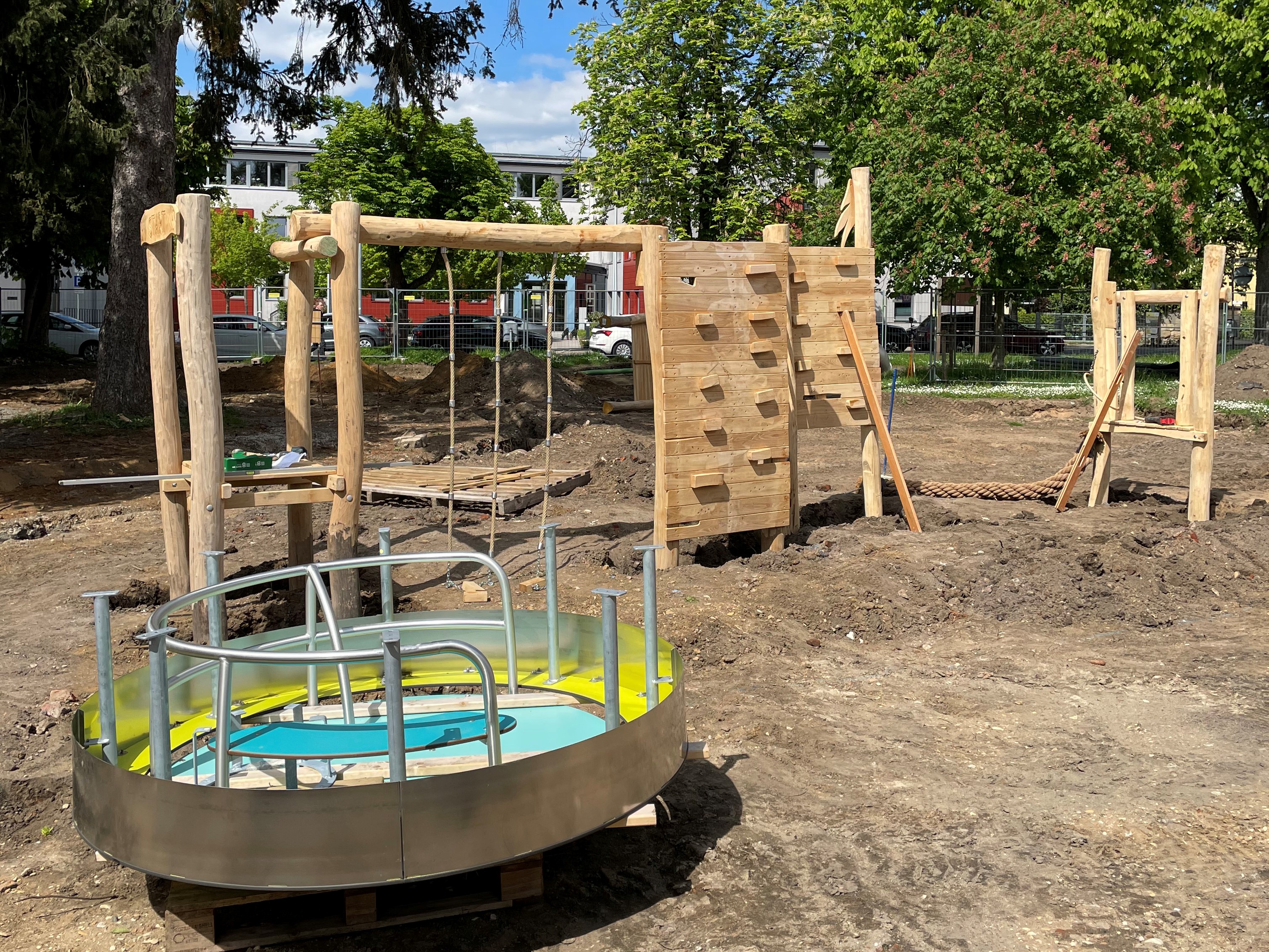 Klettergeräte und Drehkarussel werden am Streckerplatz aufgebaut. Aufbau von Spielgeräte mit grißem Holzanteil und einen Drehkarussel aus Metall auf einem Spielplatz.