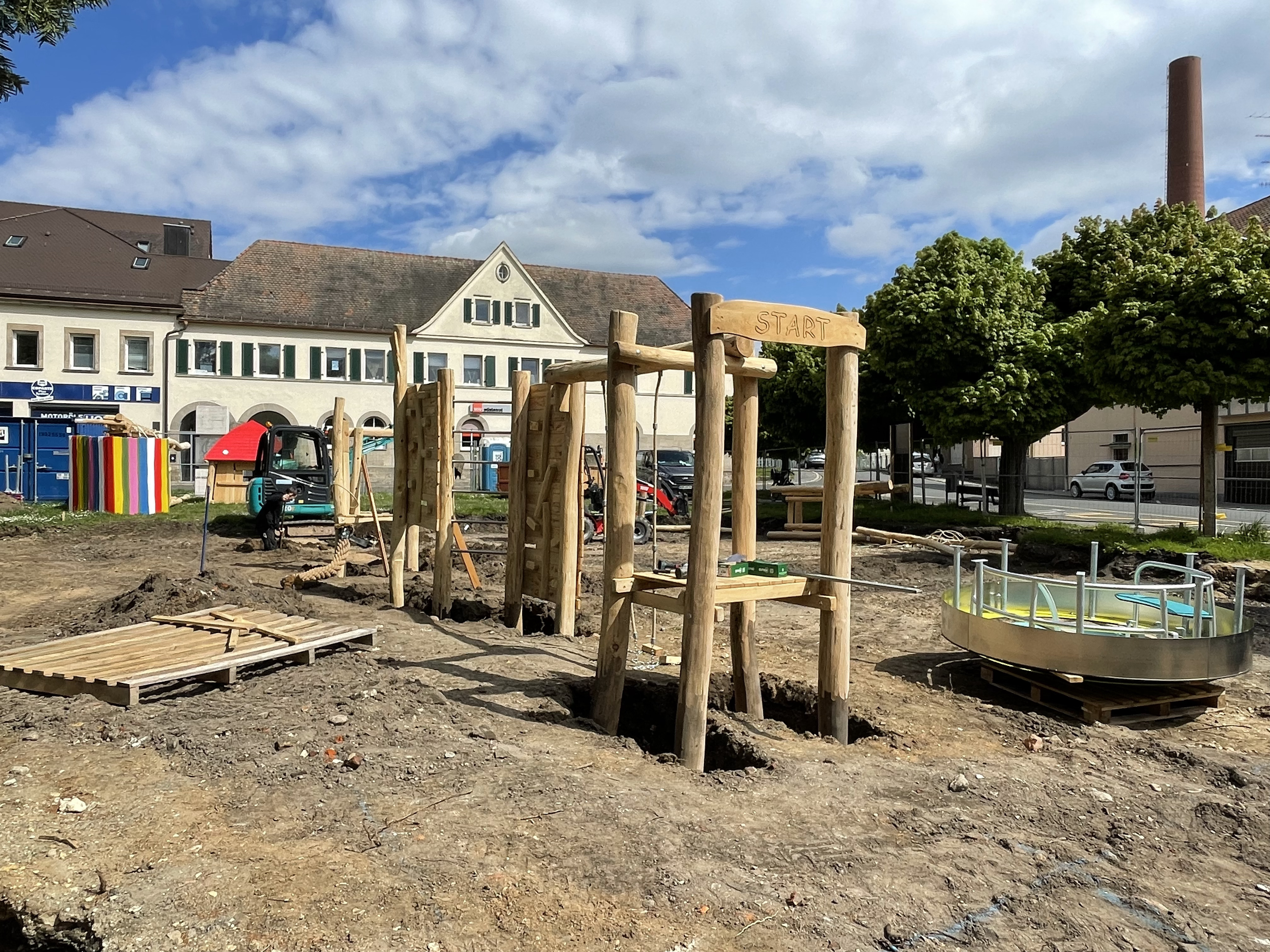 Aufbau der Spielgeräte am Streckerplatz. Aufbau von Spielgeräte mit grißem Holzanteil auf einem Spielplatz.